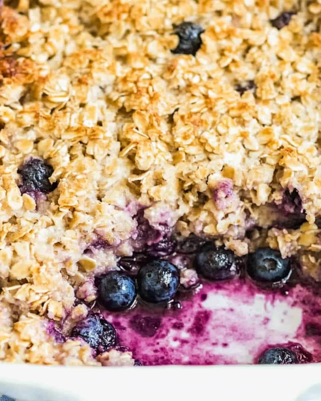 Baked oatmeal with fresh blueberries in a white dish.