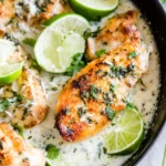 Creamy Coconut Lime Chicken served in a skillet, garnished with fresh cilantro and lime wedges.