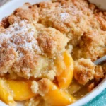 Freshly baked Southern Peach Cobbler in a baking dish with golden-brown crust and juicy peach filling.