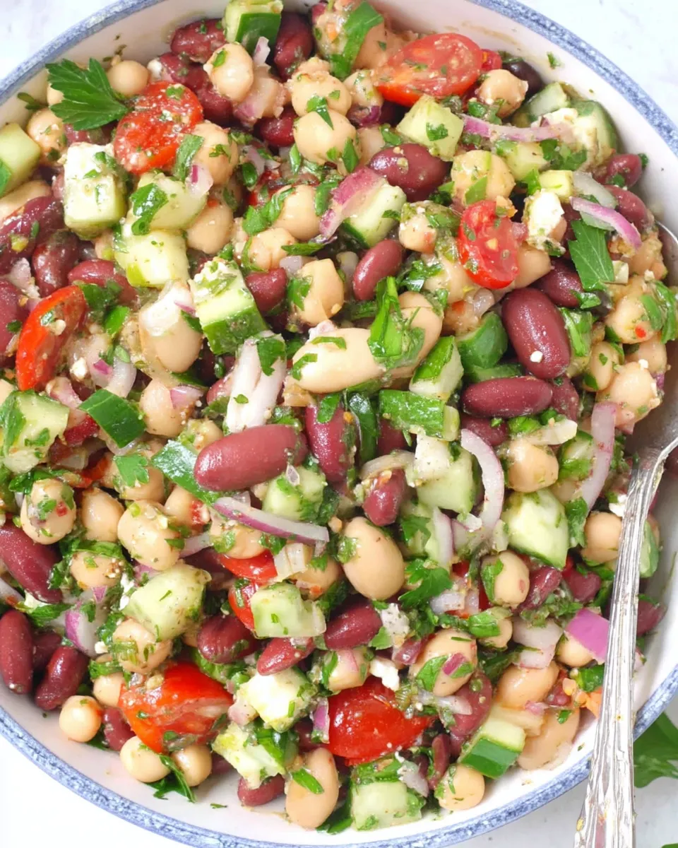 A colorful Double Bean Mediterranean Salad with chickpeas, kidney beans, cucumber, tomatoes, red onion, olives, and fresh herbs tossed in olive oil and lemon dressing.