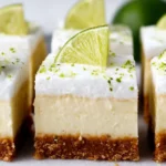 Square-shaped Key Lime Pie Bars with a creamy lime filling and golden graham cracker crust, topped with lime zest and served on a white plate.