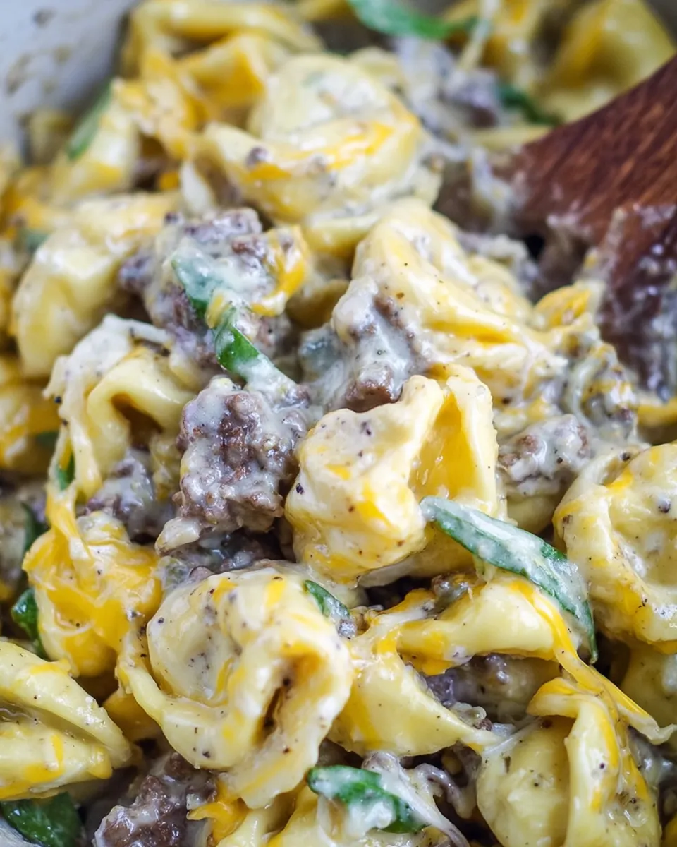 Philly cheesesteak tortellini pasta with melted cheese, peppers, and onions in a skillet