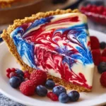 Red, white, and blue swirl pie with creamy layers and fresh berries on a white plate