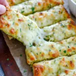 Cheesy zucchini breadsticks on wooden board