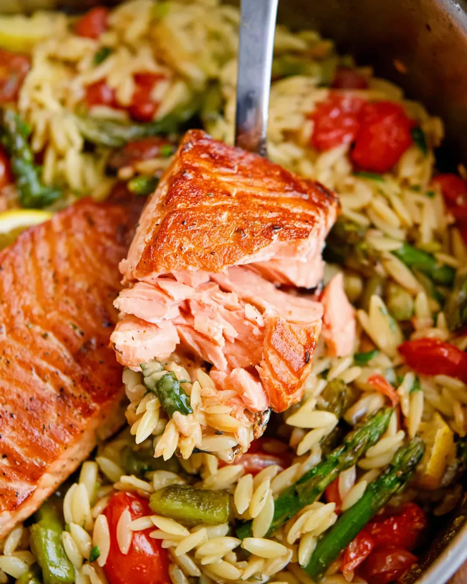 Creamy lemon salmon orzo skillet with fresh herbs and lemon slices in a black pan