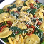 Ravioli tossed with spinach, sun-dried tomatoes, and artichokes in a creamy sauce