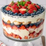 Red, white, and blue berry tiramisu in a glass dish with layered cream, strawberries, blueberries, and raspberries