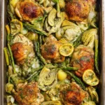 Mediterranean chicken in a skillet with artichokes, asparagus, lemon slices, and herbs