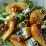 Caramelized pear and blue cheese salad with walnuts on a white plate