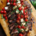 Sliced grilled flank steak topped with balsamic tomatoes and mozzarella