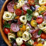 Colorful bowl of Italian tortellini pasta salad with salami and mozzarella cubes