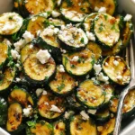 Roasted zucchini salad with feta and fresh herbs on a white plate