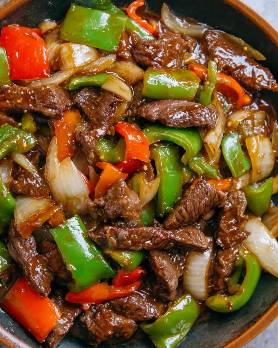 Slow cooker pepper steak with onions served over rice in a bowl.