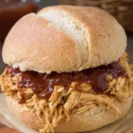 : Crockpot BBQ chicken shredded and served on a sandwich bun with coleslaw.