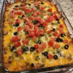 Crockpot taco casserole with beef, beans, and melted cheese, served in a baking dish.