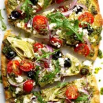 Mediterranean flatbread pizza topped with olives, tomatoes, and feta.