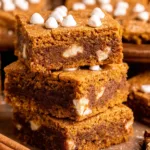 Chewy Pumpkin Blondies with warm fall spices, sliced into squares on a parchment-lined tray.
