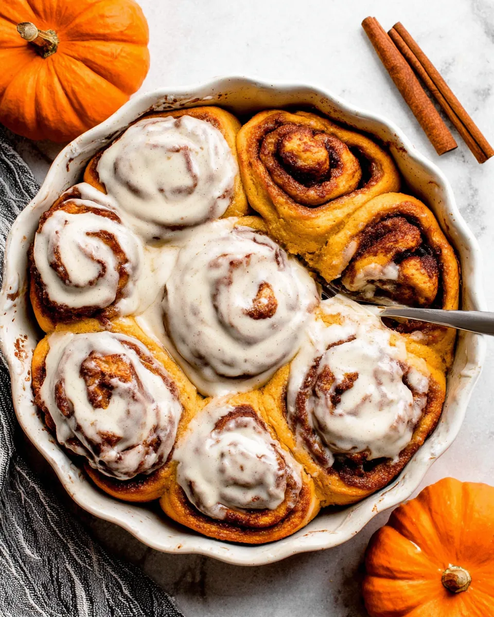 Pumpkin Cinnamon Rolls stacked with maple icing and fall decor