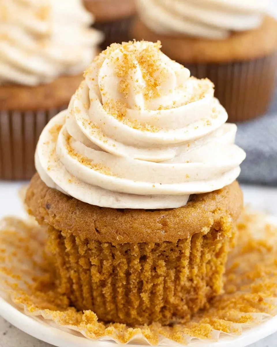 Pumpkin cupcakes topped with cream cheese frosting and cinnamon dust