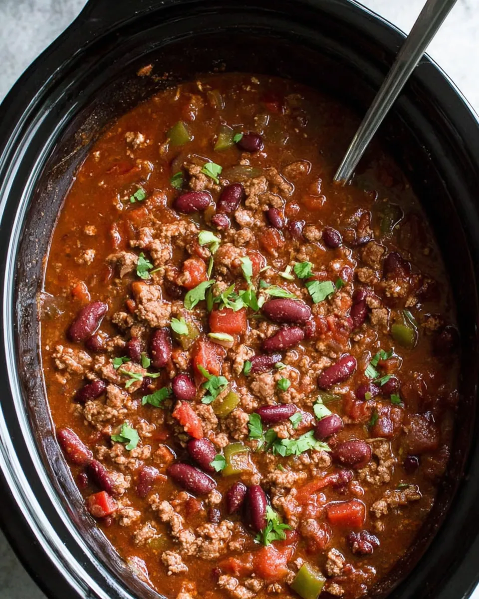 Bowl of slow cooker chili topped with cheese, sour cream, and cilantro.
