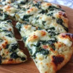 Garlic and spinach white pizza baked on a golden cottage cheese crust, topped with melted mozzarella and fresh basil.